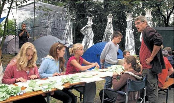 3.000 Papierflieger wollen die Sch&uuml;ler bis Sonntag falten. &raquo;WolfRabe&laquo; (rechts) leitet sie beim Kunstprojekt an.